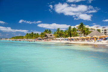 People swimming near white sand beach with umbrellas, bungalow bar and cocos palms, turquoise caribbean sea, Isla Mujeres island, Caribbean Sea, Cancun, Yucatan, Mexico