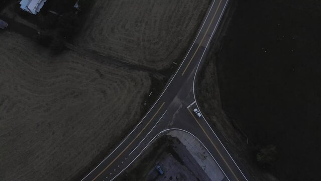 Aerial, top-down shot of a vehicle making a stop at a T-junction.  Just before dark.