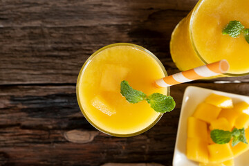 Mango smoothies orange colorful fruit juice beverage healthy high protein the taste yummy in glass on wood background from top view.
