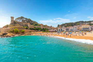 Fototapeta premium The sandy Playa Grande beach at the seaside Spanish town of Tossa de Mar, Spain, with the historic 12th Century castle above it on the Costa Brava coast.