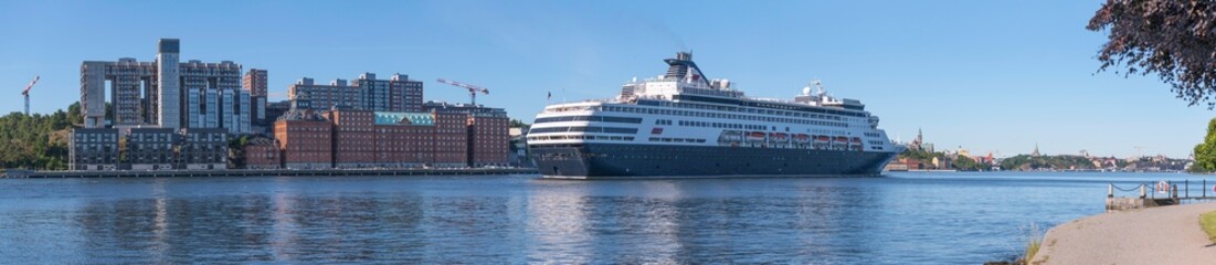 Fototapeta na wymiar A cruise ship arriving between the apartment islands Kvarnholmen and Djurgården, a sunny summer day in Stockholm