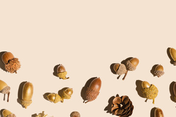 Top view autumn pattern from natural materials, natural golden painted acorns oak tree, dry seeds on beige background. Autumnal minimal style flat lay, aesthetics fall image, above view