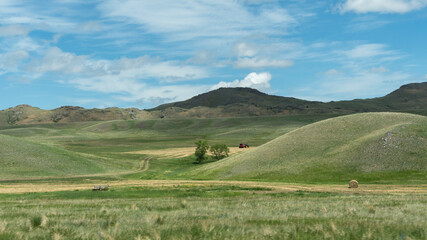 Fototapeta na wymiar A tractor at work in the rolling green hills of western Montana.