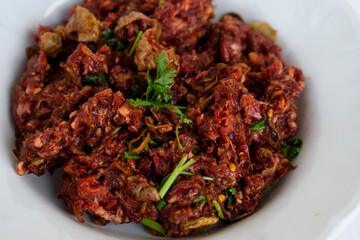 Spicy raw minced meat pork salad on dish. Concept : weird food. Thai norther local eating style. Delicious but risk with germs that cause deafness or parasites, so better to eat well-done cooked. 