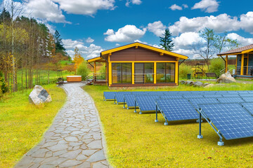 Solar battery in autumn countryside. Sunlight technology. Power station. Solar battery in front of wooden houses. Photoelectric energy. Solar electricity battery . Environmental IVF source energy. - obrazy, fototapety, plakaty