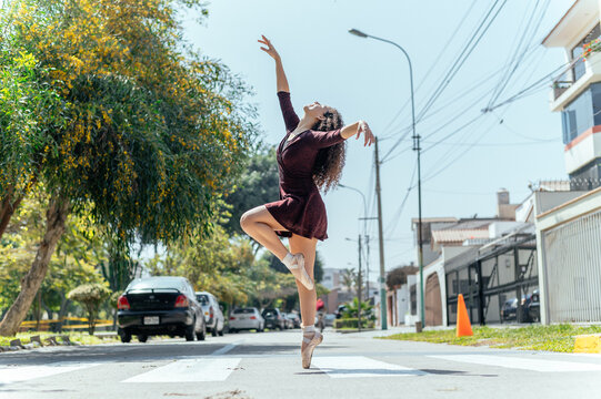 Ballerina in leotard and skirt and ballet shoes dancing on the street
