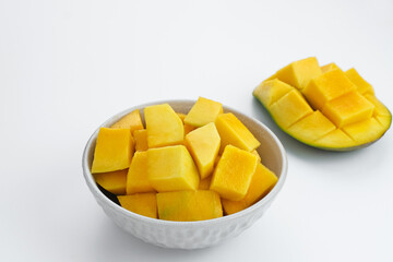 A bowl of sliced ​​fresh mango cubes served in white bowl on white background. Copy space
