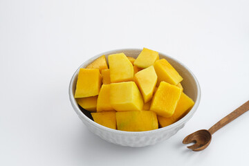 A bowl of sliced ​​fresh mango cubes served in white bowl on white background. Copy space
