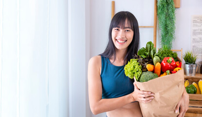 Asian Japanese woman holding shopping bag from supermarket full of organics vegetables and fruits for healthy food and vegetarian salad with copy space