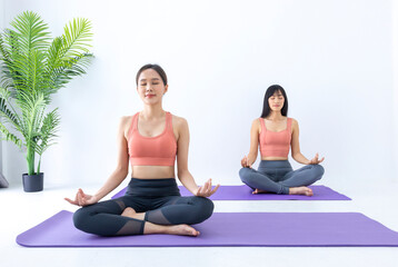 Fototapeta premium Asian woman practicing yoga indoor with easy and simple position to control breathing in and out in meditation pose