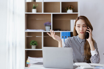 Asian woman talking on the phone, she is a salesperson in a startup company, she is calling customers to sell products and promotions. Concept of selling products through telephone channels.