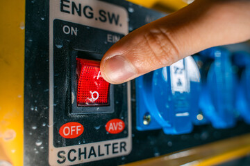The finger presses the start button of a gasoline electric generator close-up