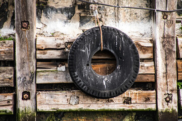 Fine art image of an old car tire hanging on a harbour wall
