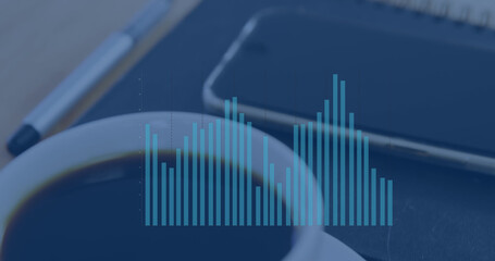 Image of graph processing data over notebook, smartphone and coffee cup on desk