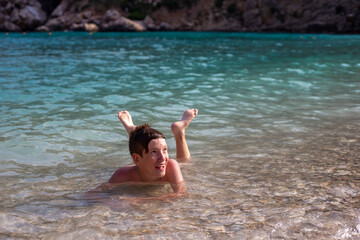 White happy boy swims in the sea. Summer fun in the water. Beach holiday
