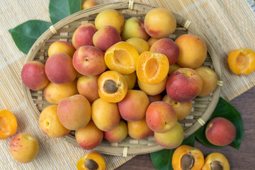 Apricot fruit on bamboo basket on wooden table, fresh Apricot with leaf.