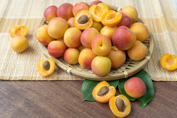 Apricot fruit on bamboo basket on wooden table, fresh Apricot with leaf.