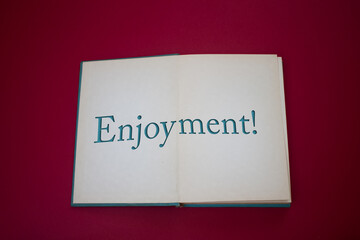 Enjoyment word in opened book with vintage, natural patterns old antique paper design.