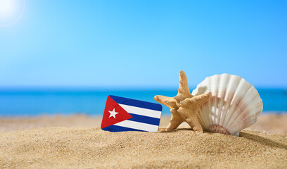 Fototapeta na wymiar Tropical beach with seashells and Cuba flag. The concept of a paradise vacation on the beaches of Cuba.