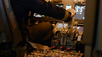 Aviation crew flying airplane with engine lever to throttle, using dashboard command buttons to...