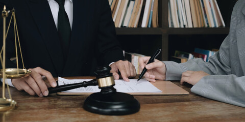 Business woman and lawyers discussing contract papers with brass scale on wooden desk in office. Law, legal services, advice, Justice concept.