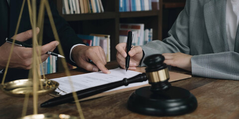 Business woman and lawyers discussing contract papers with brass scale on wooden desk in office. Law, legal services, advice, Justice concept