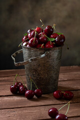 Fototapeta na wymiar A metal vintage bucket on a wooden table filled with cherries.