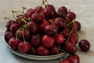 A white ceramic dish with a cherry in the center. Light background.