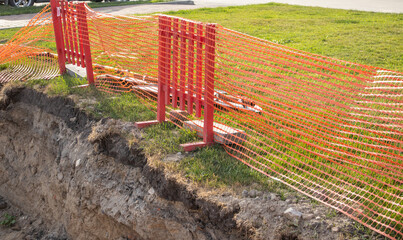 Protective fencing on the edge of the trench during the repair work of underground utilities....