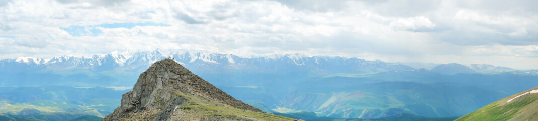 Dramatic panoramic landscape of rocky mountains among the clouds, banner format