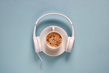 Headphones and coffee cup on a light blue background. Top view. Flat lay composition with copy space