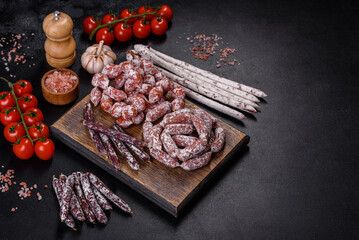 Delicious dry sausage with walnuts on a concrete table. Dry cured fuet sausage on a dark background