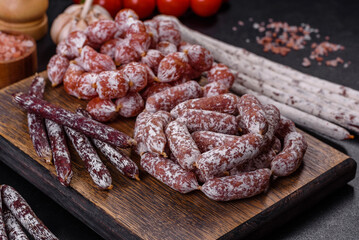 Delicious dry sausage with walnuts on a concrete table. Dry cured fuet sausage on a dark background
