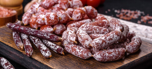 Delicious dry sausage with walnuts on a concrete table. Dry cured fuet sausage on a dark background