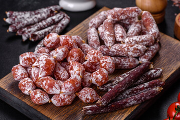 Delicious dry sausage with walnuts on a concrete table. Dry cured fuet sausage on a dark background