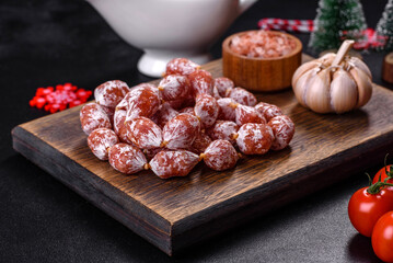 Delicious dry sausage with walnuts on a christmas table. Dry cured fuet sausage on a dark background