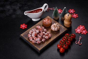 Delicious dry sausage with walnuts on a christmas table. Dry cured fuet sausage on a dark background