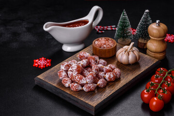 Delicious dry sausage with walnuts on a christmas table. Dry cured fuet sausage on a dark background