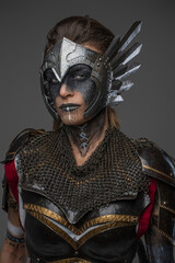 Fototapeta Portrait of woman amazon with brown hairs from past dressed in dark armor isolated on gray background. obraz