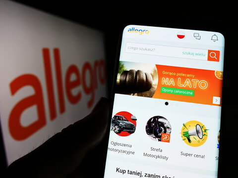 Stuttgart, Germany - 07-10-2022: Person holding cellphone with website of Polish e-commerce company Allegro.pl Sp. z o. o. on screen with logo. Focus on center of phone display.