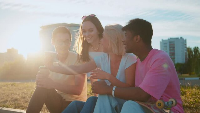 Young Multi-ethnic Hipster Best Friends On Summer Video Chatting Using Smartphone At A Beach. Four Young Multiracial People Spending Time Together. Friendship, Communication, Youth A Lifestyle Concept