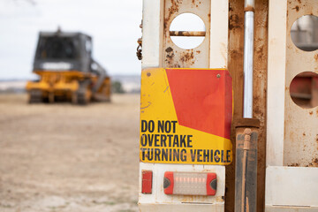 rear of truck with warning sign and blurred machine in background