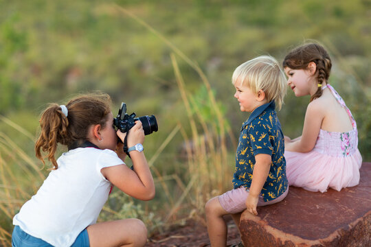 little girl playing photographer photographing other kids