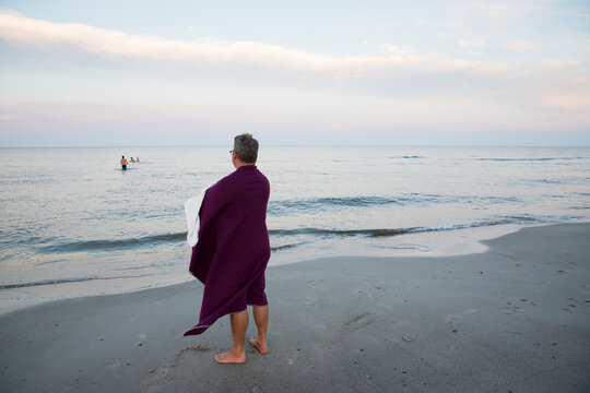 Man wrapped in towel standing on beach