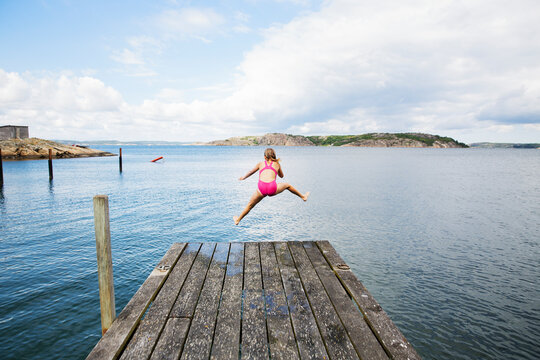 Girl diving into sea from jetty