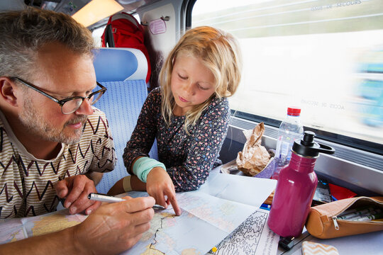 Father and daughter looking at map on train