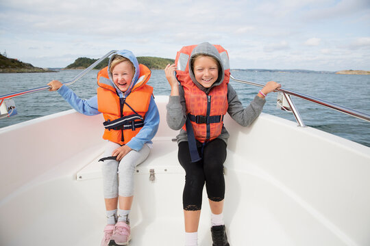Smiling girls in life jackets sitting on boat