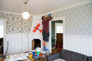 Man applying wallpaper in house