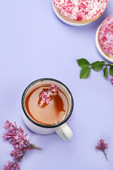 Lilac flowers with cup of tea on colourful background.
