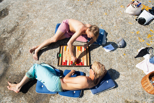 Young men lying down playing backgammon on rock